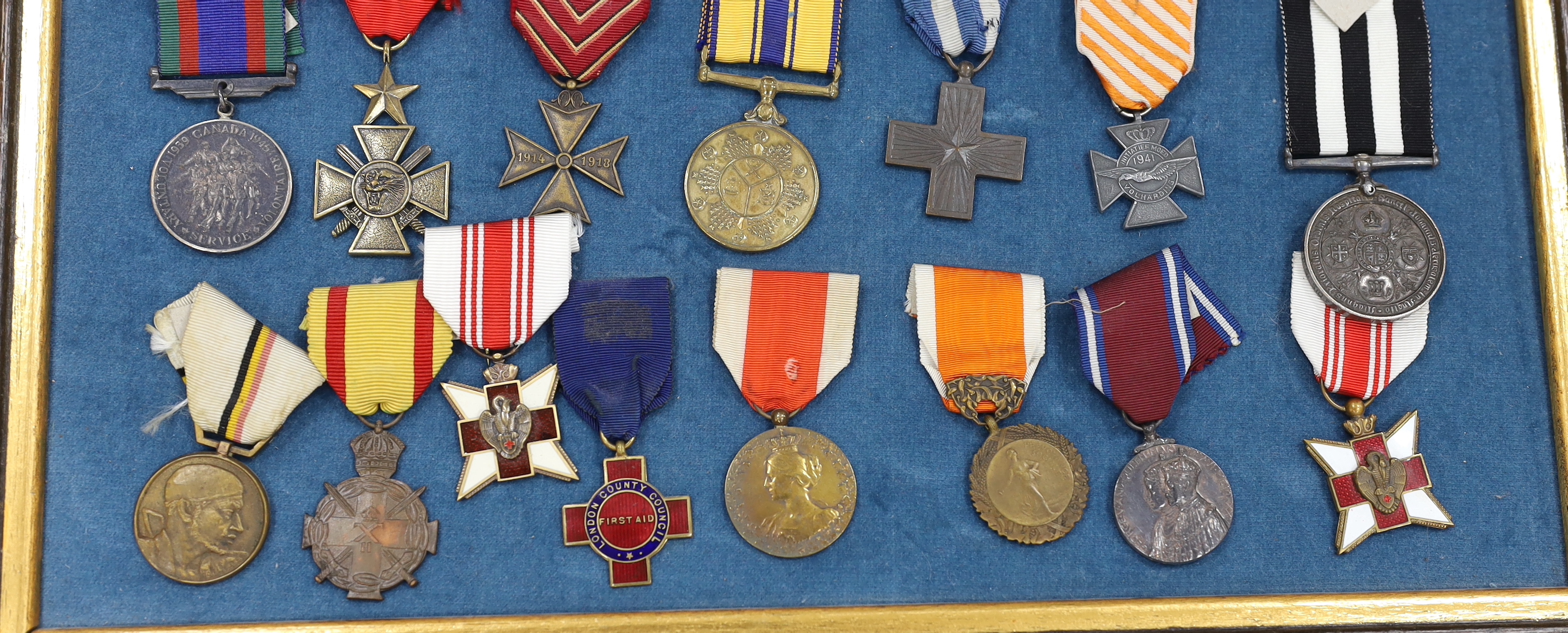 Twenty-seven medals and awards mounted in oak frames, including; French 1939-45 War Medal, Poland Lenino Cross 1943, Romanian Commemorative Medal, Belgium Red Cross Medal, etc. together with cloth shoulder titles for the